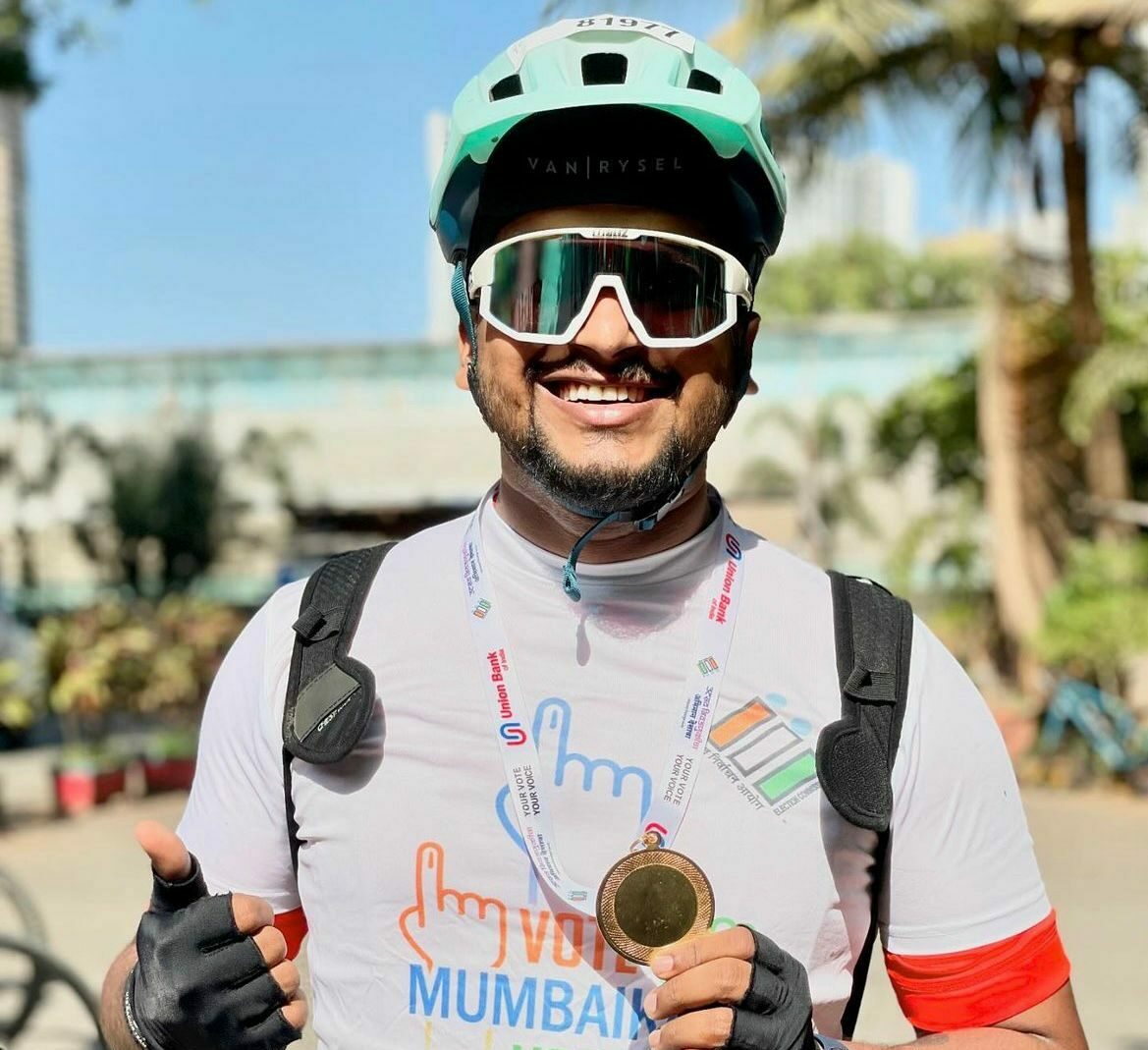 a happy cyclist showing off his winning medal wearing helmet and accessories , available at our cycle shop .